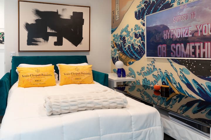 Bedroom with a large wave mural and yellow accent pillows