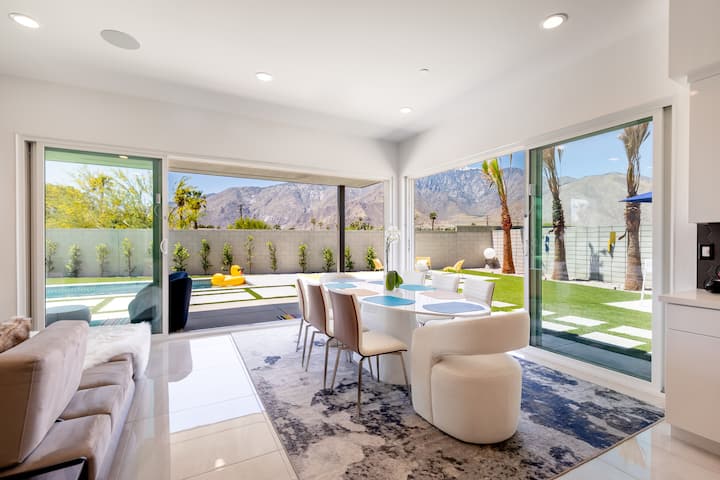 Dining table for eight beside sliding glass walls, with the backyard and mountains outside