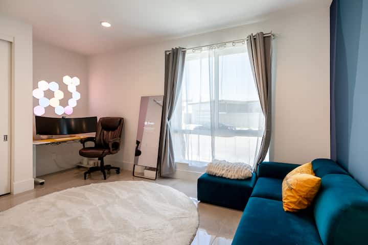 A sit/stand desk with a monitor and office chair in the corner of a guest room