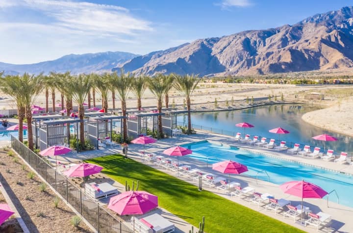 Miralon's community pool lined with pink umbrellas and palms, the mountains behind