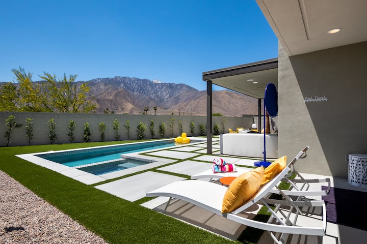 A sun lounger with yellow cushions beside the lap pool, mountains in the distance