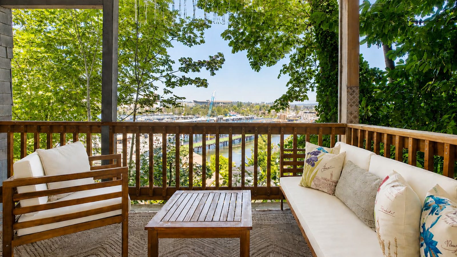 Covered balcony with outdoor seating, looking through the trees toward Portage Bay in Seattle