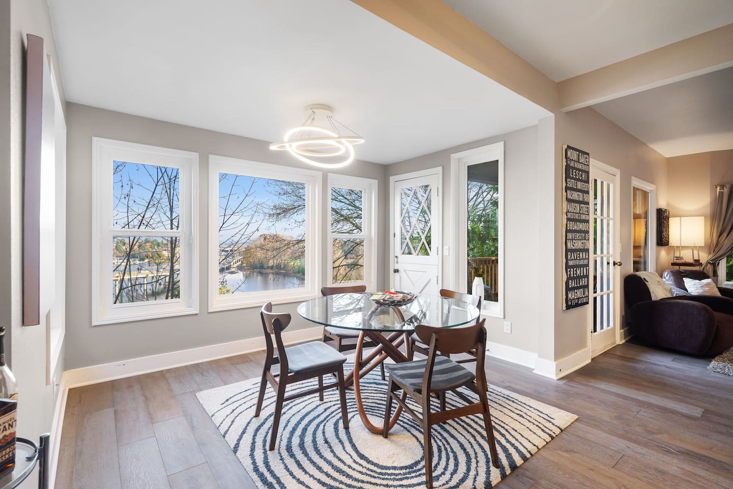 Dining table beside tall windows looking out over the trees toward the water