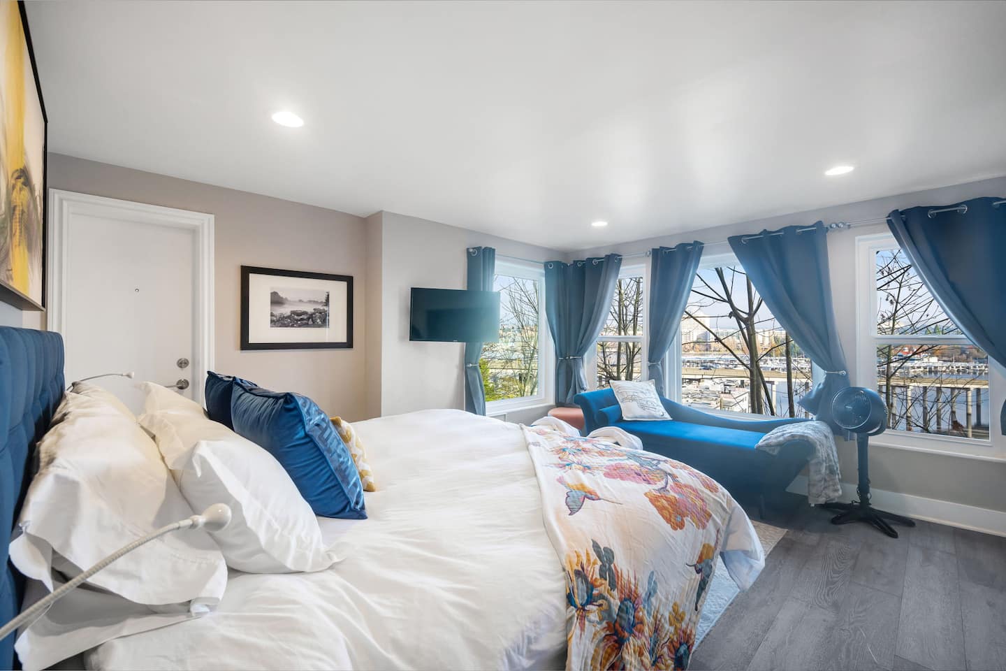 Bedroom with a king bed and blue curtains framing windows to the trees
